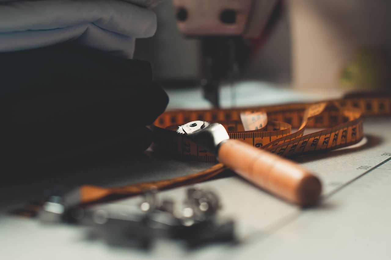 gallery-4 A detailed image of tailoring tools and fabrics on a workbench, perfect for sewing concepts.